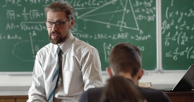 Handsome bearded teacher explaining algebra lesson to students, professional
