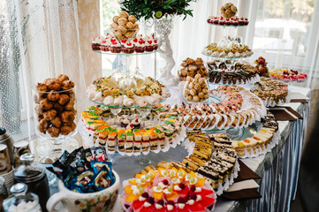 Sweet table. A plates of cakes and muffins with cream with berries. Table with sweets, candy, buffet. Dessert table for a party goodies. Close up. party reception, decorated in restaurant. candy bar