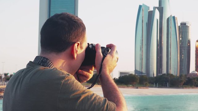 Young Caucasian Male Photographer Taking Pictures of Abu Dhabi Cityscape with Professional Photo Camera. Tourist on Vacation in Arab Middle East Countries