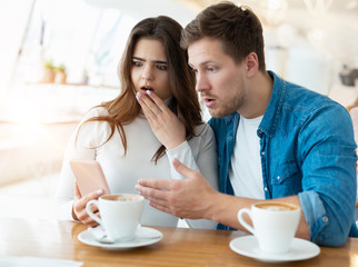 young couple sitting at cafe , handsome man and beautiful woman looking amazed, confused and bewildered, body language concept