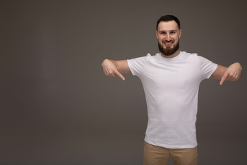 Young handsome man with beard and casual clothes and smiling to the camera while presenting.