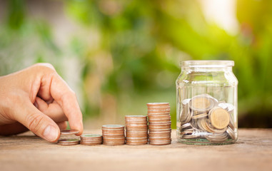 Hand putting stack coins for growing with green bokeh background. Financial, Investment, Business and Save Money concept.
