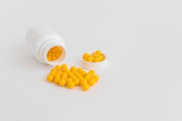 Vitamins. Antiviral drug tablets. Round yellow healthy pills and pill bottle on white background....