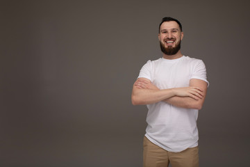 Portrait of a handsome bearded man smiling against grey background with copy space.