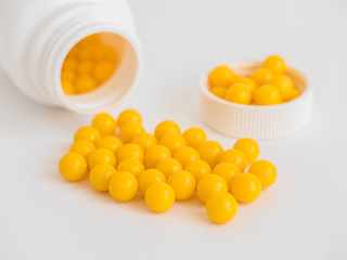 Vitamins. Antiviral drug tablets. Round yellow healthy pills and pill bottle on white background. Minimalistic concept
