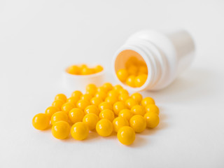 Vitamins. Antiviral drug tablets. Round yellow healthy pills and pill bottle on white background....