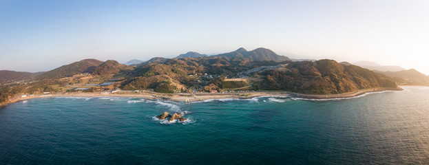 白い鳥居と夫婦岩 夕陽に輝く海岸線 全景 パノラマ 空撮
