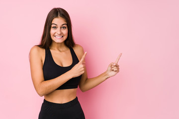 Young caucasian fitness woman doing sport isolated shocked pointing with index fingers to a copy space.