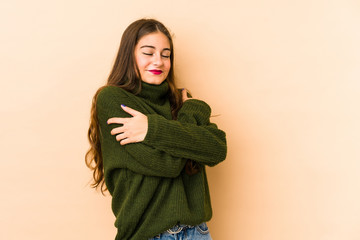 Young caucasian woman isolated en beige background hugs, smiling carefree and happy.