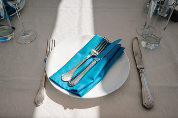 Serving, setting table. Plate and silverware cutlery linen blue napkin. Wedding table decoration....