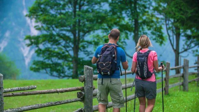 People walking down a path near a wooden fence, trekking in a popular Topla Valley in Slovenia.