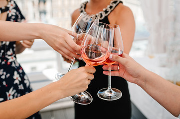 Cheers! People celebrate and raise glasses of wine for toast. Group of man and woman cheering with sparkling champagne in rooftop restaurant overlooking the city.