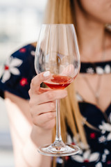 A party photo of sexy lady in dress holding a glass of wine on party. Girl, woman standing in the background and drink wine. Concept of celebrate, holiday.