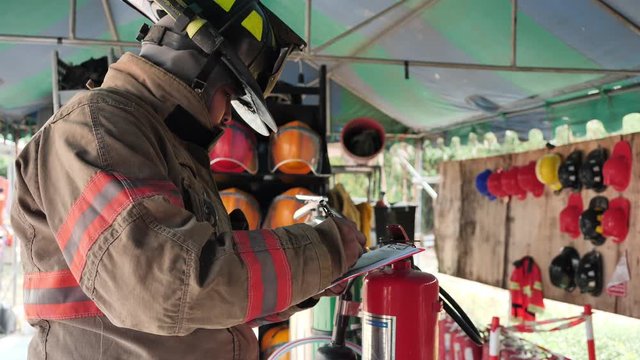 Asian fireman check Carbon Dioxide in fire extinguisher System ready In the event of a fire. Preparation for work Concept. Slow Motion