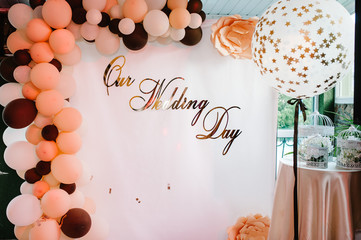 Photo-wall with text our wedding day. Wedding photo zone with balloons and free space. Colorful balloons background, brown, white, gold. Holiday concept. Wedding ceremony with beautiful decoration.