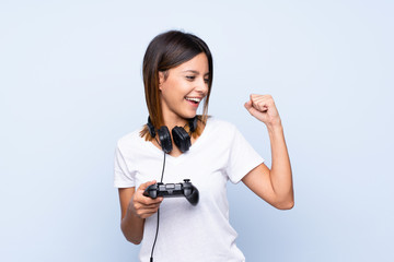 Young woman over isolated blue background playing at videogames