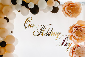 Fototapeta na wymiar Photo-wall with text our wedding day. Wedding photo zone with balloons and free space. Colorful balloons background, brown, white, gold. Holiday concept. Wedding ceremony with beautiful decoration.