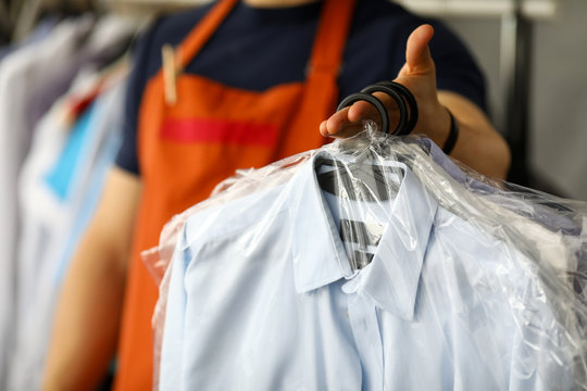 Clothes dry cleaning service worker returning shirts to customer