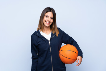 Young woman over isolated blue background with ball of basketball