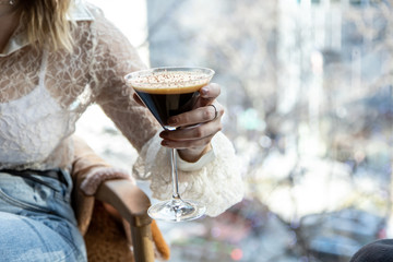 close up view of a woman's hand picking a martini glass filled with delicious chocolate coffee...