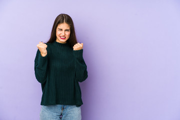 Young caucasian woman isolated on purple background upset screaming with tense hands.