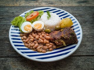 Food dish. Beans, rice, meat, salad, egg. Rustic wood background.
