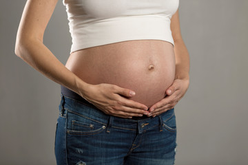 Big belly of a pregnant woman on a gray background. Close-up.