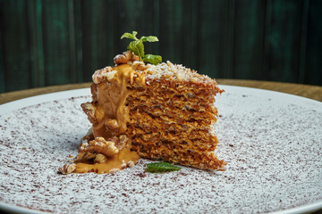 Appetizing piece of waffle cake with condensed milk and salted caramel and nuts on a white ceramic...