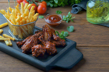 barbecue wings with French fries on a dark background