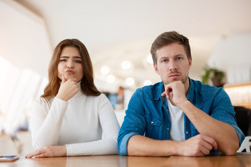 young couple beautiful woman and handsome man sitting at cafe during coffee break, both looking...
