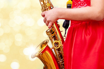 Girl with saxophone on golden background with bokeh_