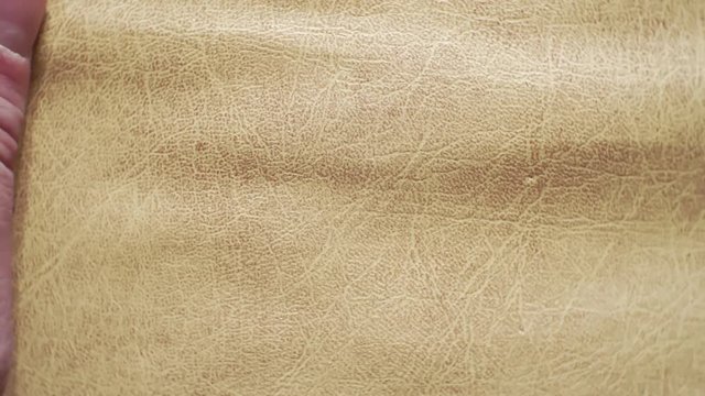 fingers touch the surface of a soft light surface leather.