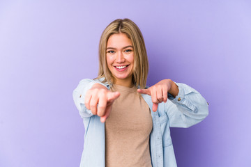 Young blonde caucasian woman isolated cheerful smiles pointing to front.