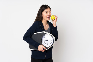 Young asian woman isolated on white background with weighing machine and with an apple