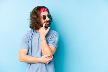 Young long hair man wearing a festival hipster look isolated relaxed thinking about something looking at a copy space.