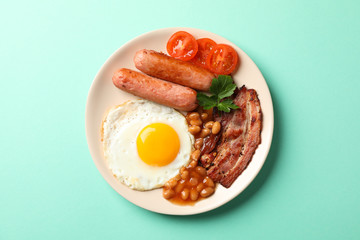 Delicious breakfast or lunch with fried eggs on mint background, top view