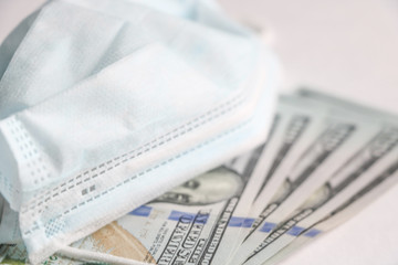 Medical mask on dollars as a symbol of increasing prices for protecting the respiratory tract from the virus. There is a place for copyspace.