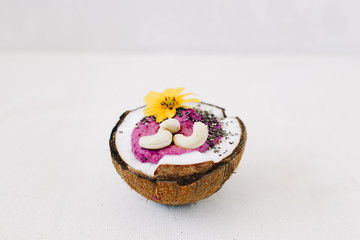 healthy Breakfast berry smoothie with Chia seeds and cashew nuts in a natural coconut plate on a white table