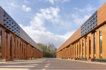View from the ground of a wooden bridge in the middle of a field