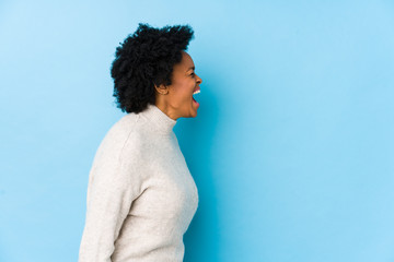Fototapeta na wymiar Middle aged african american woman against a blue background isolated shouting towards a copy space