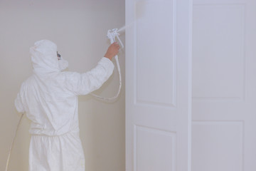 Fototapeta na wymiar Master painting wood doors with spray gun processing painting door house