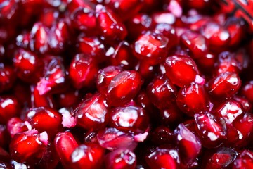 Macro full frame close up of red shiny juicy pomegranate seeds (focus on center)