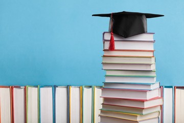 Stack of colorful school books and graduated hat