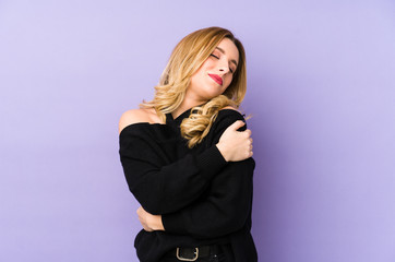 Young blonde woman isolated hugs, smiling carefree and happy.