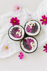 healthy Breakfast berry smoothie with Chia seeds and cashew nuts in a natural coconut plate on a white table with pink flowers