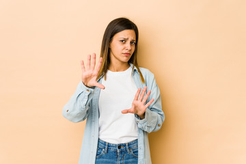 Young woman isolated on beige background rejecting someone showing a gesture of disgust.