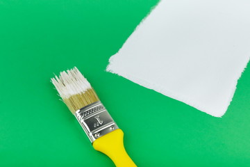 yellow paint brush and white stroke on a green background close up
