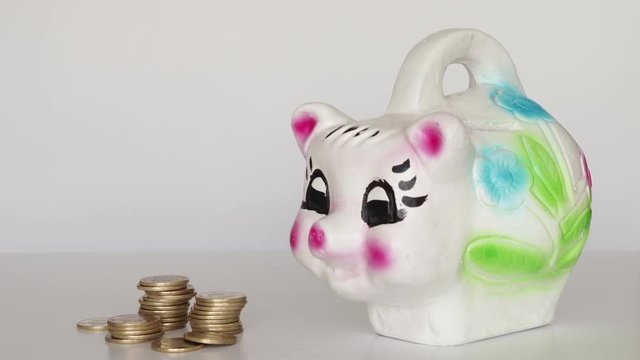 Hand puting 10 pesos coin in mexican piggy bank from the rigth