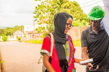 young african woman paying a mechanic who helped fixed her car via mobile transfer