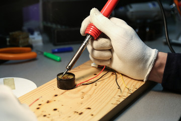 electrician hands are working with soldering iron in workshop close up